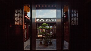 A traditional wooden gate with a view of a courtyard featuring potted plants and a small tree. - Chaozhou Manju Inn (Chaozhou)
