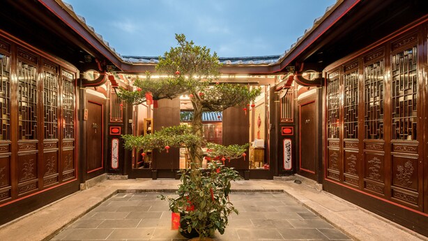 A traditional courtyard with wooden doors and a central tree. - Chaozhou Manju Inn (Chaozhou)