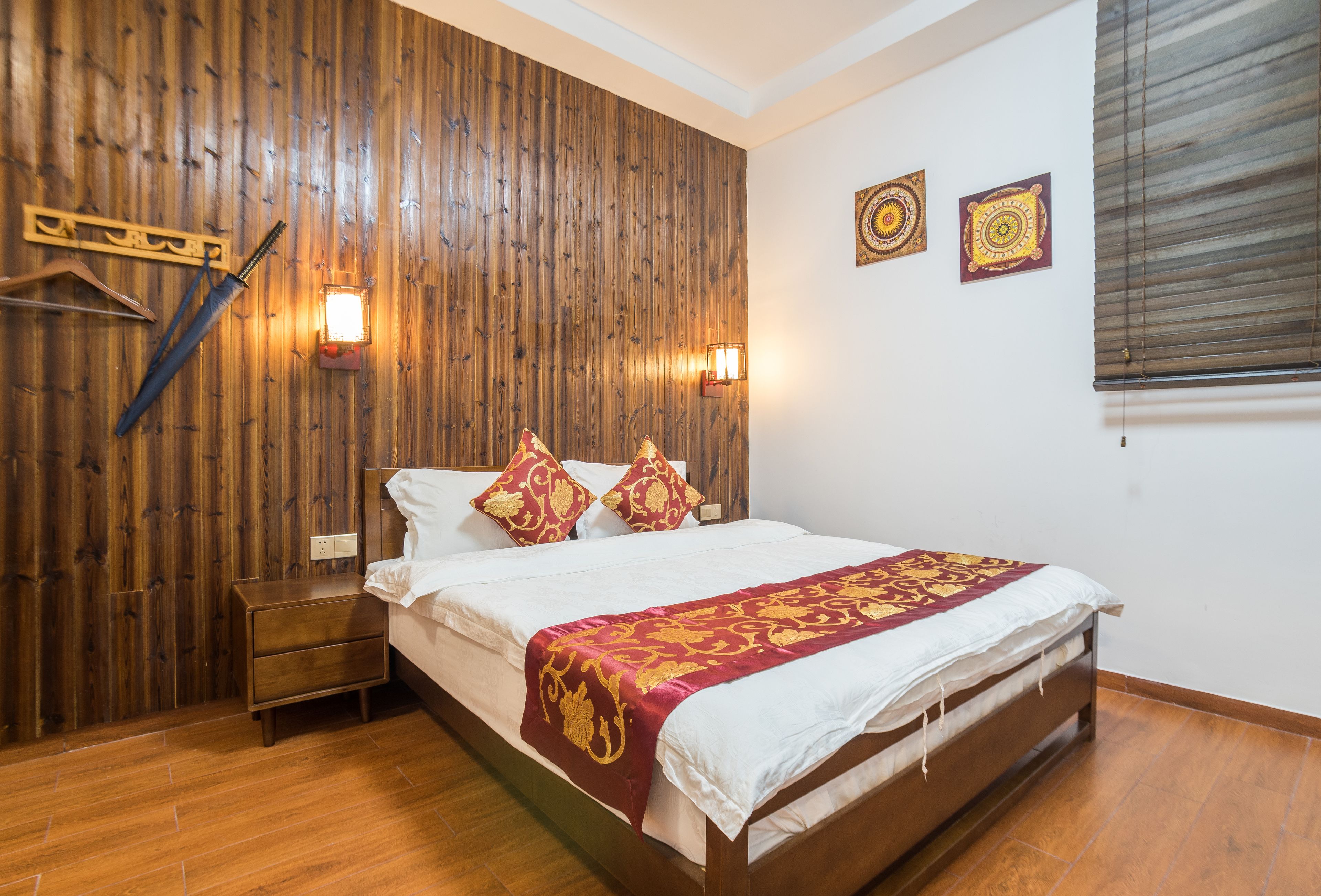 Ein Schlafzimmer mit einer Holzwand, einem Bett mit weißer und roter Bettwäsche, einem Nachttisch und zwei Wandleuchten.