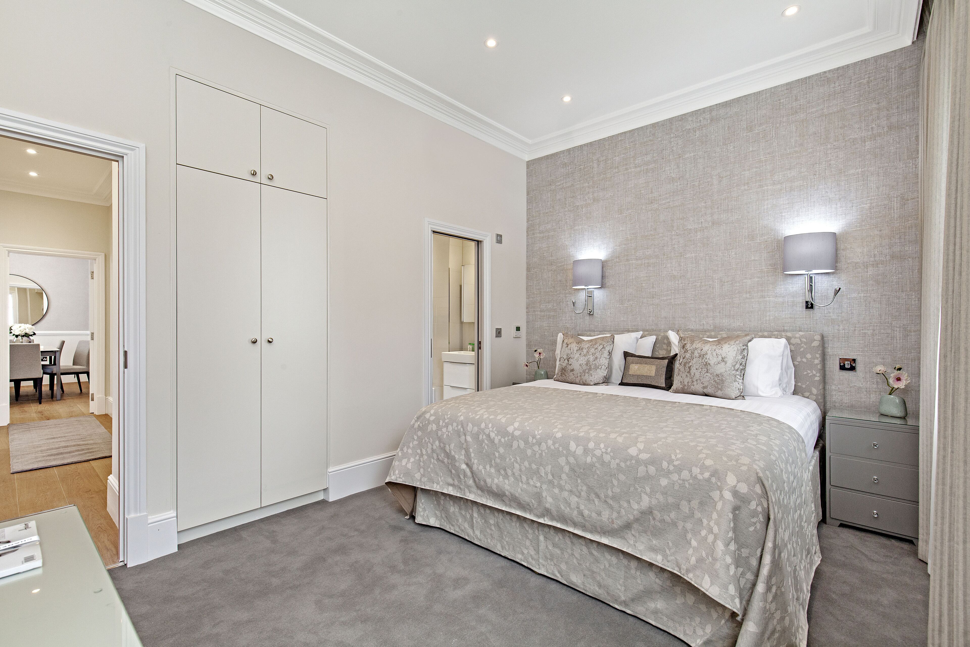 A bedroom with a large bed, a wardrobe, a bedside table, and a nightstand.