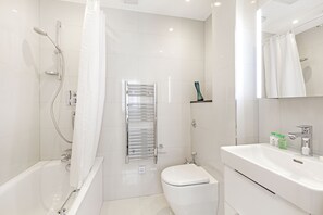 A modern bathroom with a bathtub, toilet, and sink. - Chesham Court (London)