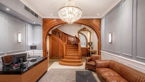 Un hall d’entrée spacieux avec un grand escalier, un comptoir de réception et un canapé en cuir.
