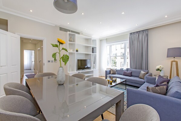 A modern living room with a dining area, a sofa set, and a TV. - Chesham Court (London)