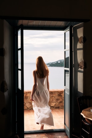 A room with an open door leading to a balcony with a view of the sea. - Patmos Eye Boutique Hotel & Villas (Patmos)