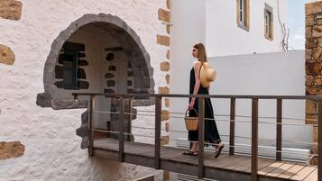 A person walking on a wooden deck with a stone wall and a metal railing.