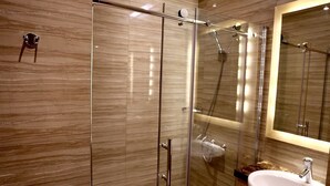 A modern bathroom with a glass shower enclosure, a marble backsplash, and a white sink. - Grand Citihub Hotel at Panakkukang (Makassar)