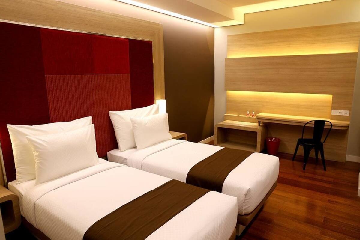 Ein Hotelzimmer mit zwei Betten, einem Schreibtisch und einem Stuhl.