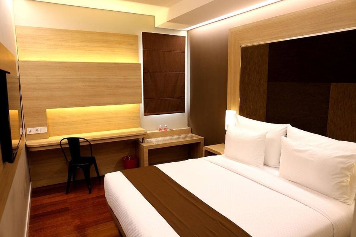 Ein modernes Hotelzimmer mit einem großen Bett, einem Schreibtisch, einem Sessel und einem kleinen Tisch mit Spiegel.