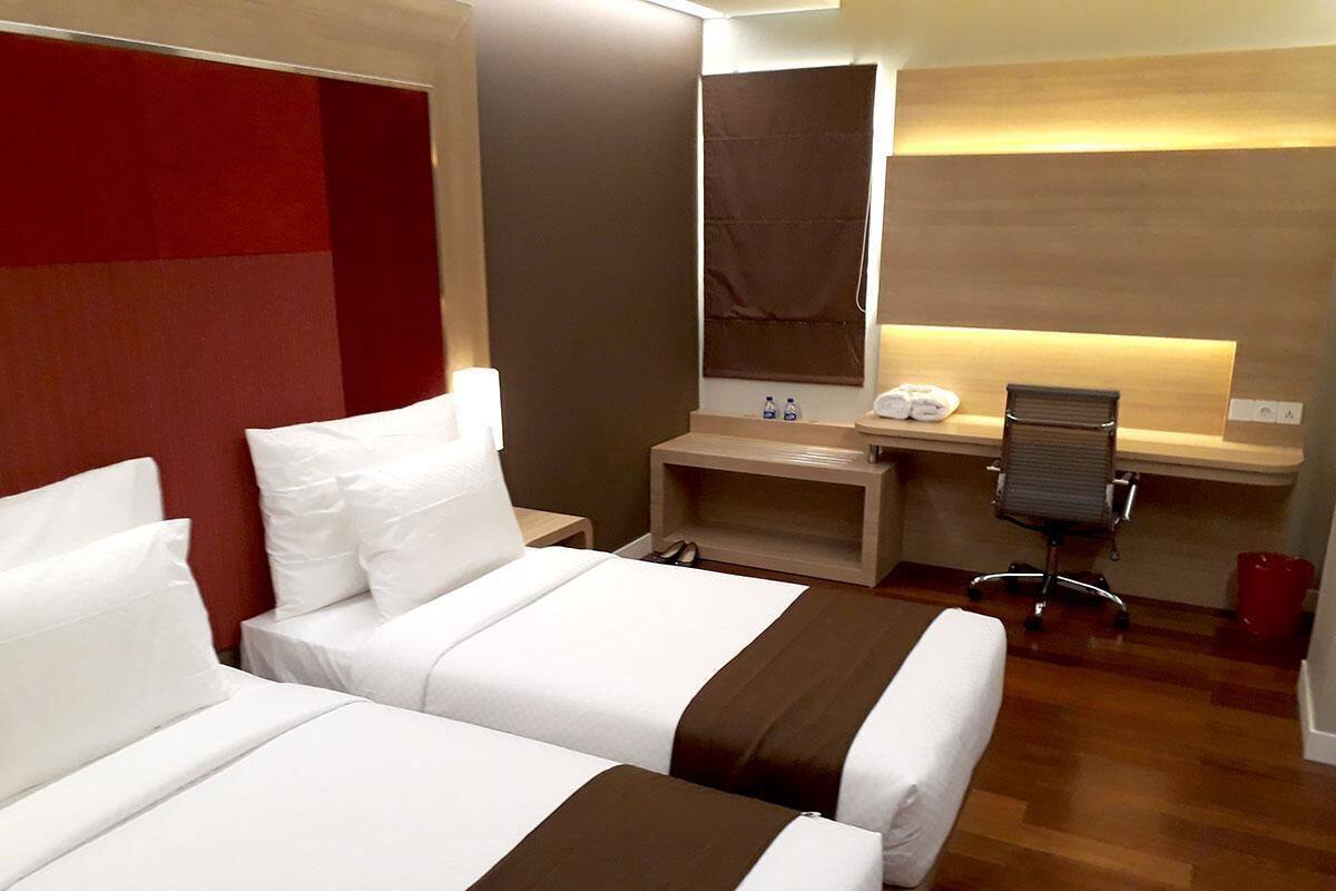 Ein Hotelzimmer mit zwei Betten, einem Schreibtisch, einem Sessel und einem kleinen Badezimmer.
