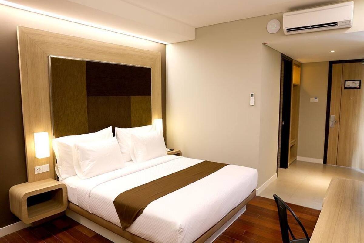 Ein Hotelzimmer mit Bett, Nachttisch, Lampe und Klimaanlage.