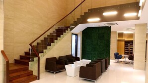 A modern lobby with a staircase, seating area, and a green wall. - Grand Citihub Hotel at Panakkukang (Makassar)