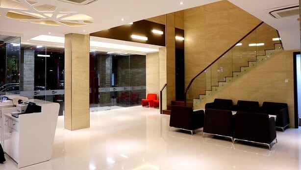 A modern reception area with a glass wall, a staircase, and seating. - Grand Citihub Hotel at Panakkukang (Makassar)