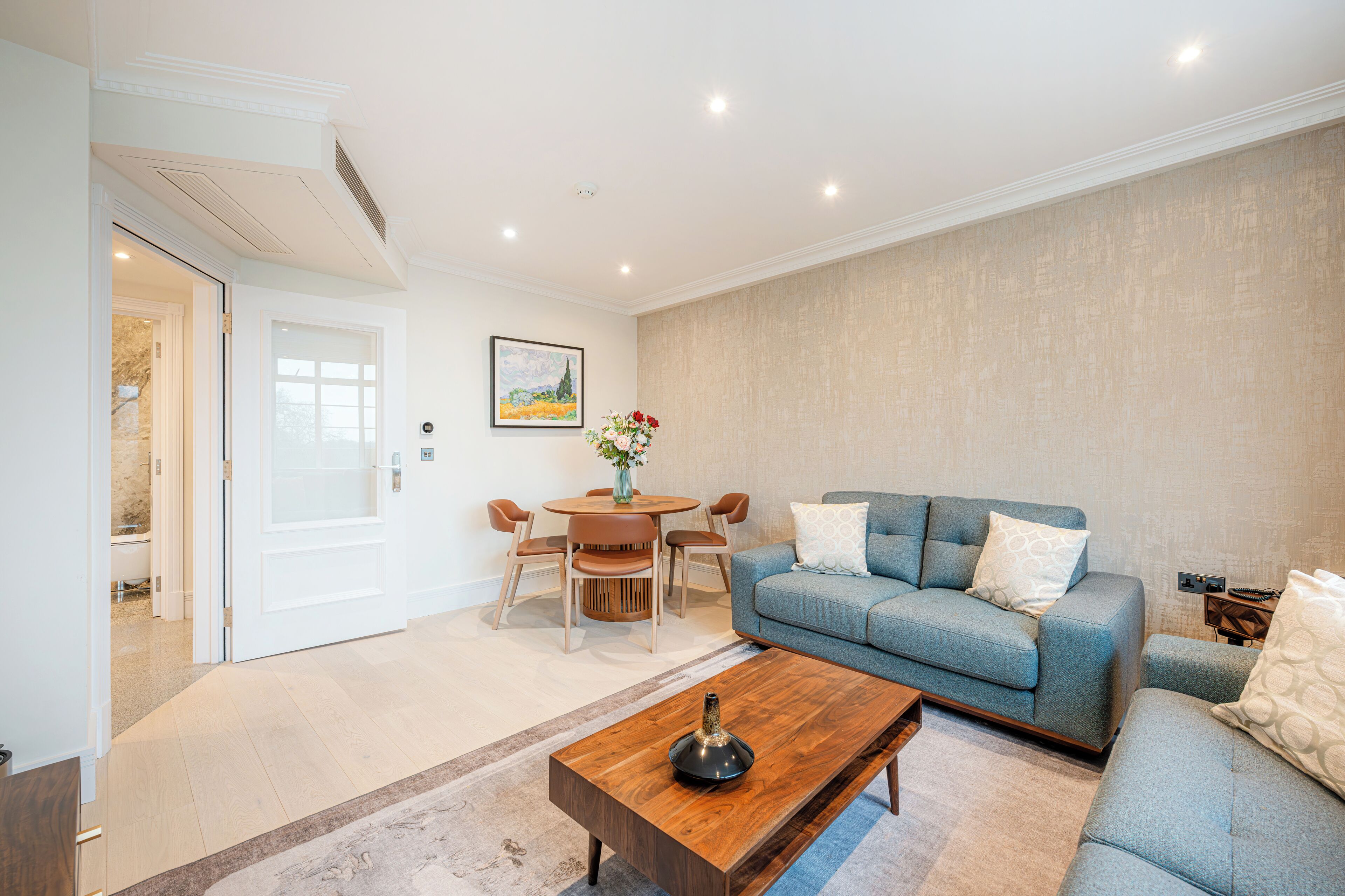 Uma sala de estar com sofá, mesa de centro e um espaço de refeições com cadeiras e mesa.