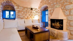 Une pièce chaleureuse avec un mur en pierre, un canapé blanc, une table basse en bois et une cheminée.