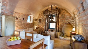 Une pi èce rustique aux murs de pierre, avec une table en bois, un canapé blanc et une grande fenêtre.