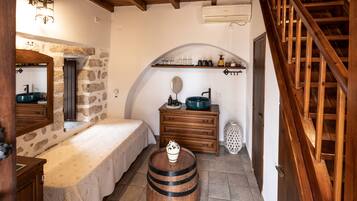Un baño rústico con pared de piedra, muebles de madera, un taburete de madera y una escalera de madera.