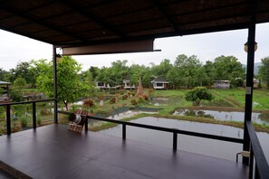 A covered outdoor area with a view of a water body and surrounding greenery.