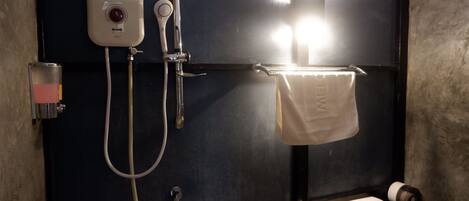 Un baño con pared negra, toallero blanco, inodoro y cabina de ducha con panel de control.