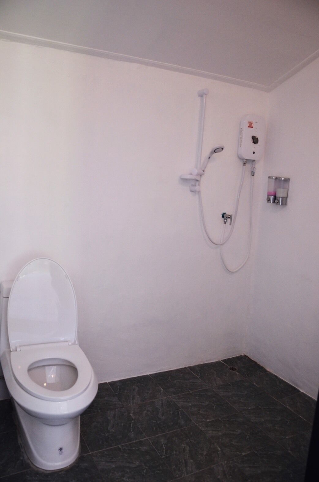 A small, clean bathroom with a toilet, a shower, and a hand dryer.