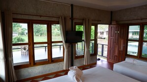 Habitación de hotel con dos camas, ventanas amplias, un televisor y vistas al exterior.