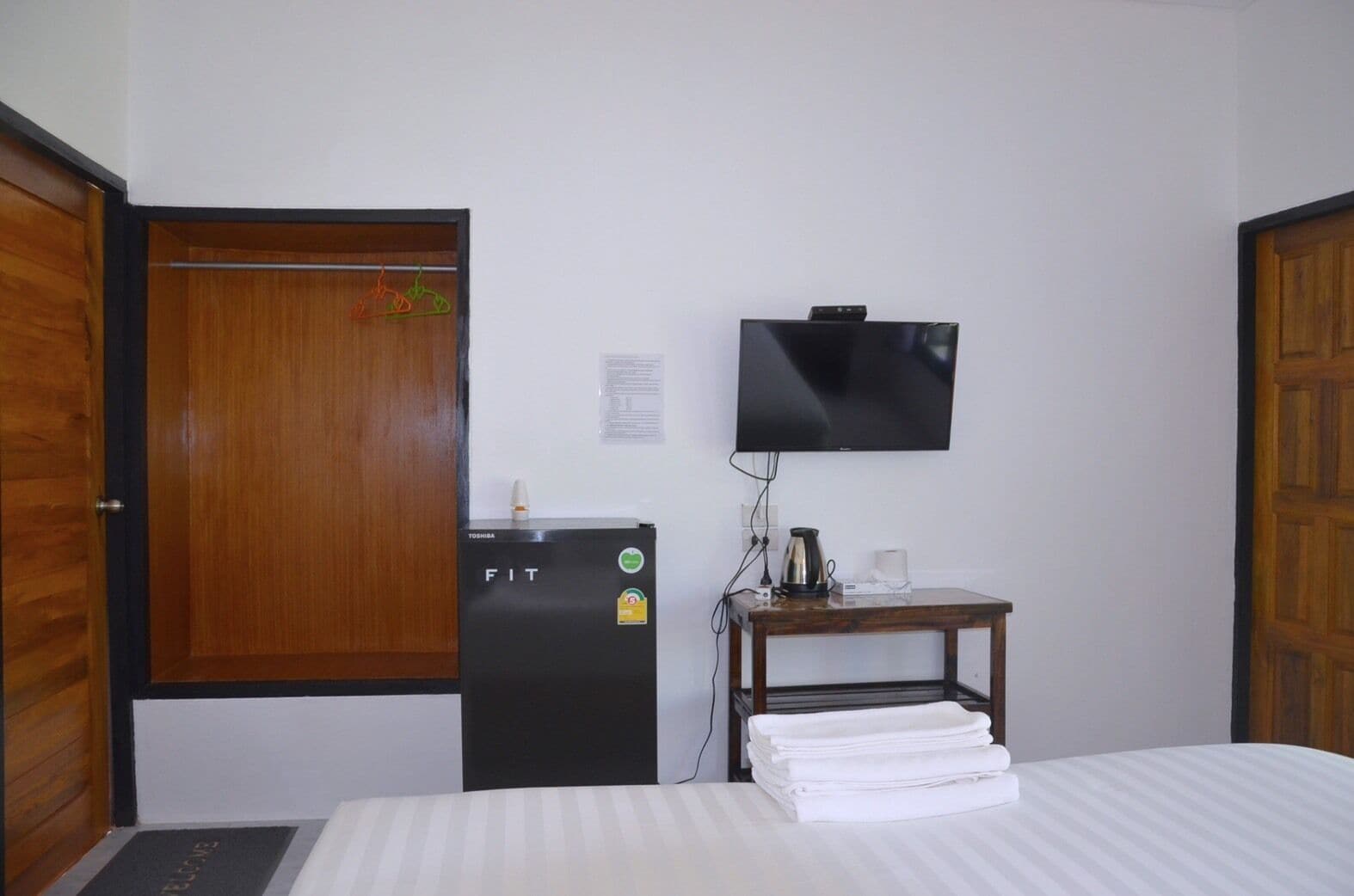 Una habitación de hotel con una cama, un escritorio con televisor, un refrigerador y un armario de madera.