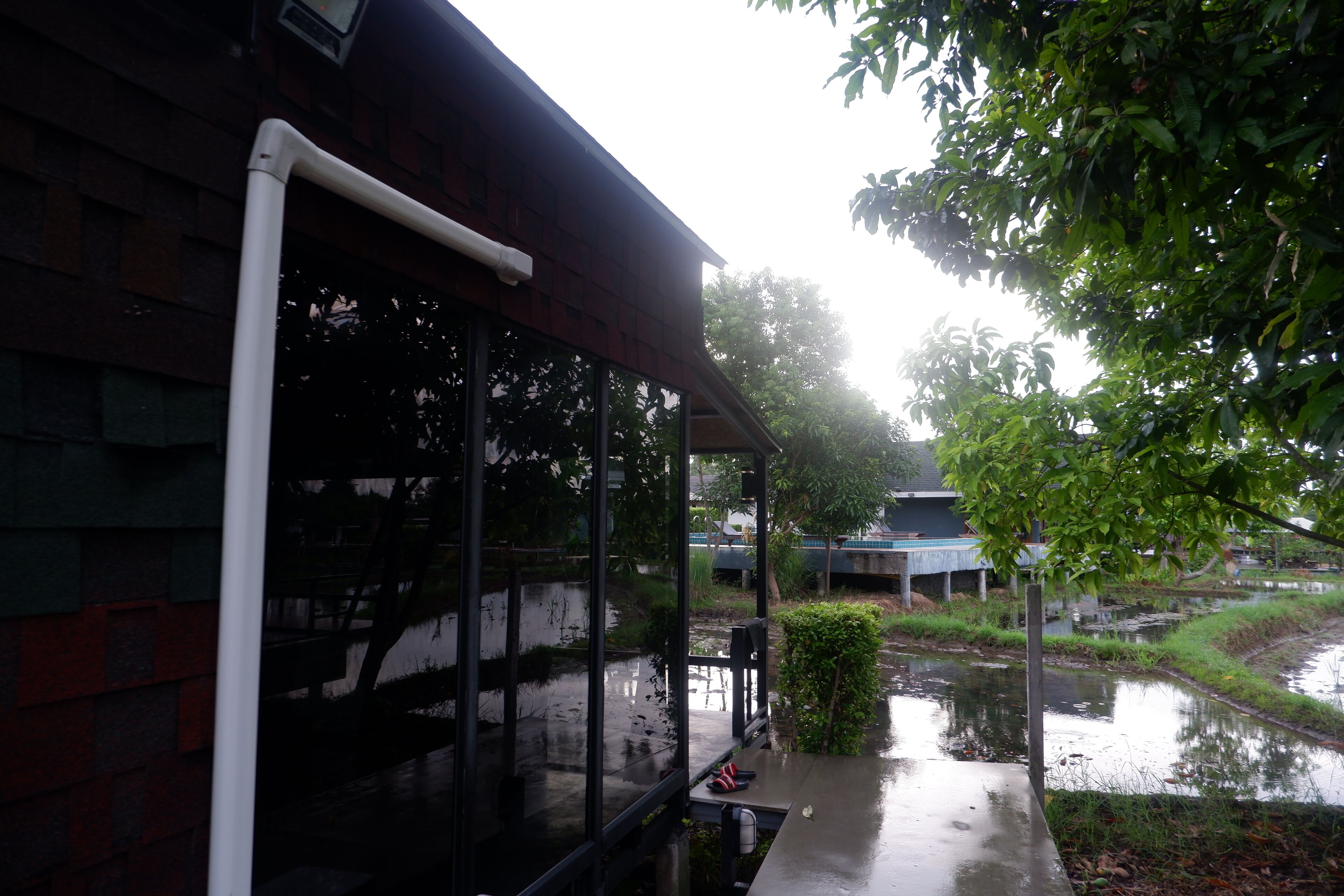 A covered outdoor area with a brick wall, a metal railing, and a view of a water body.