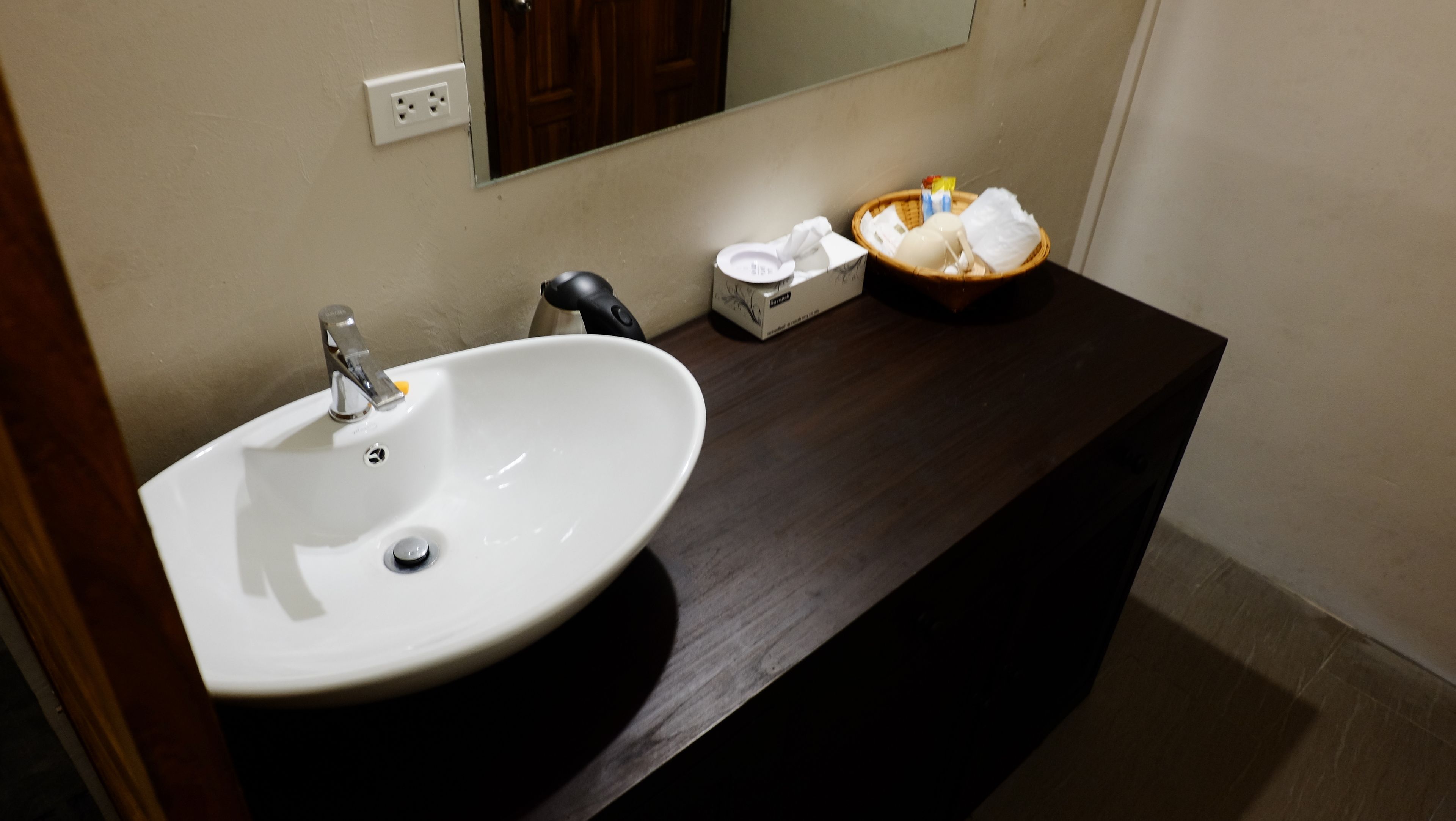 A bathroom with a white sink, a mirror, and a dark wooden countertop.