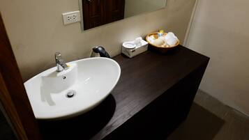 A bathroom with a white sink, a mirror, and a dark wooden countertop.