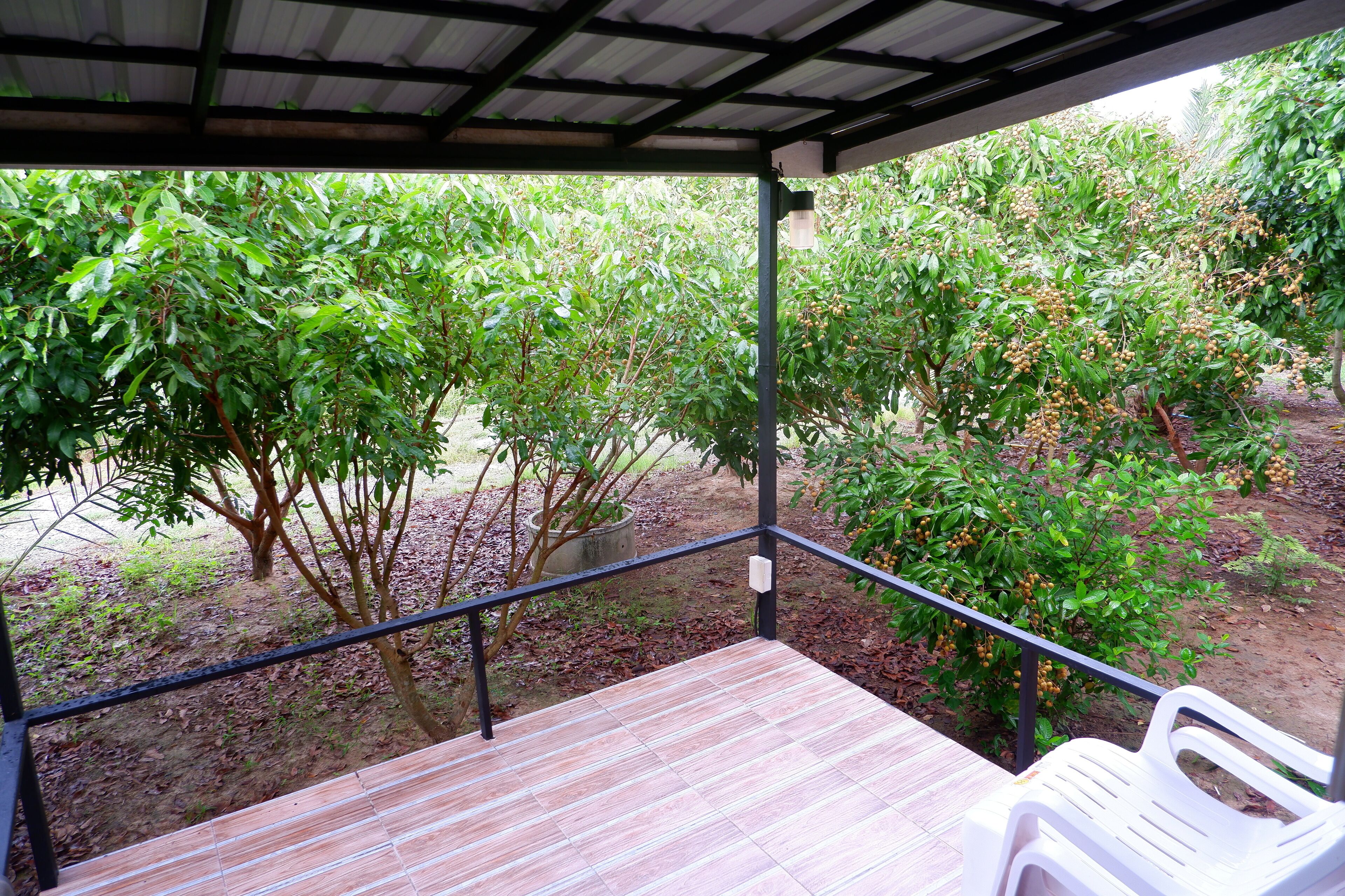 A covered outdoor area with a wooden deck and a white plastic chair.