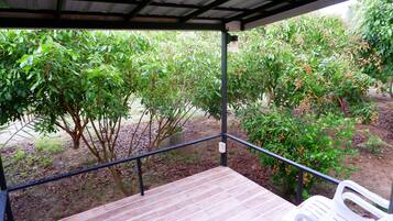 A covered outdoor area with a wooden deck and a white plastic chair.