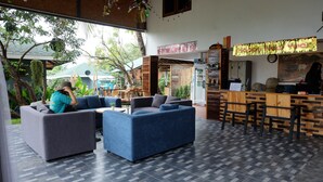 Un área de lounge moderna con sofás y un bar, con un cartel que dice 'Merry Xmas & Happy New Year'.