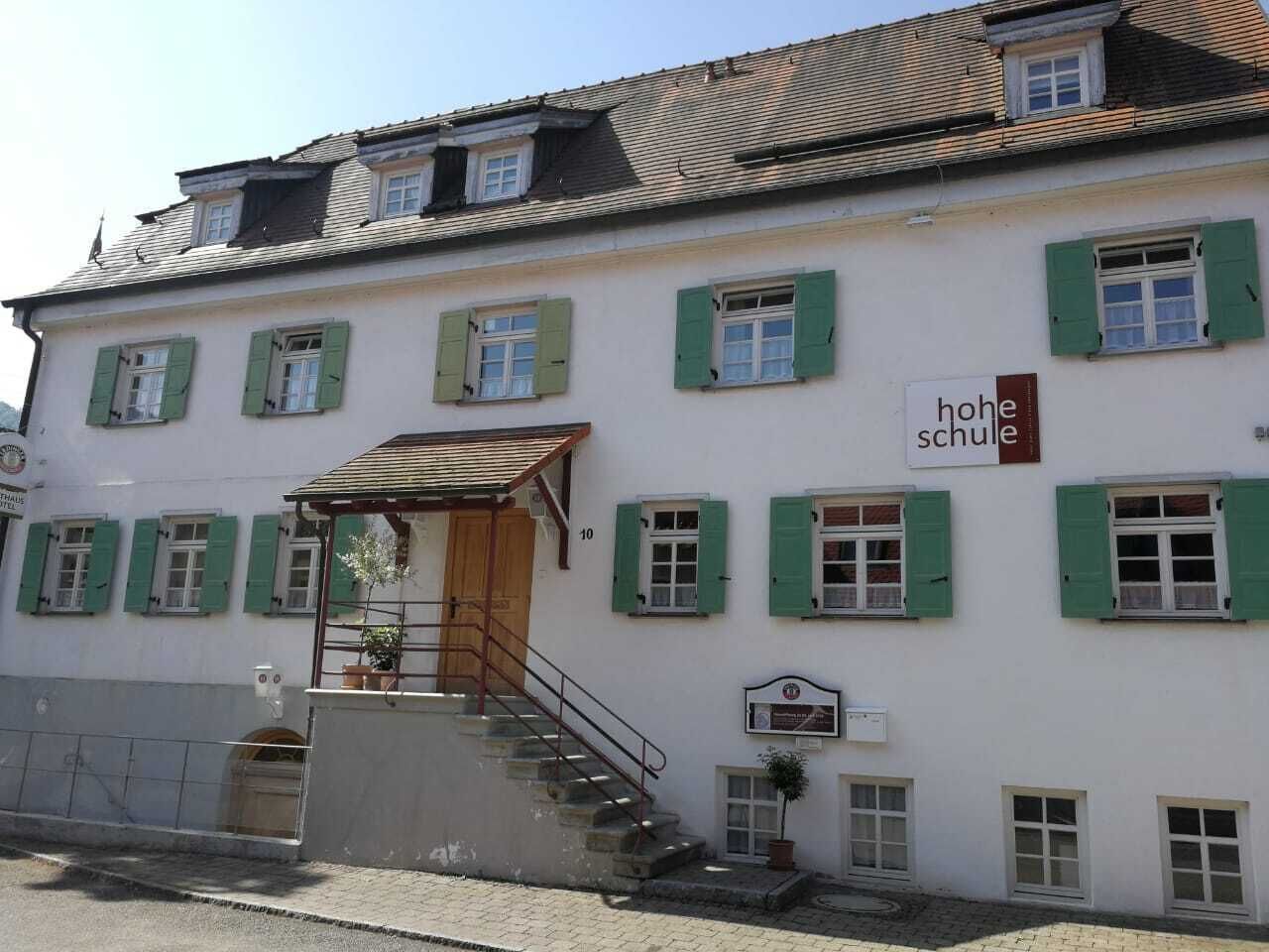 A building with a sign reading "hohe schule" and a staircase leading to the entrance.