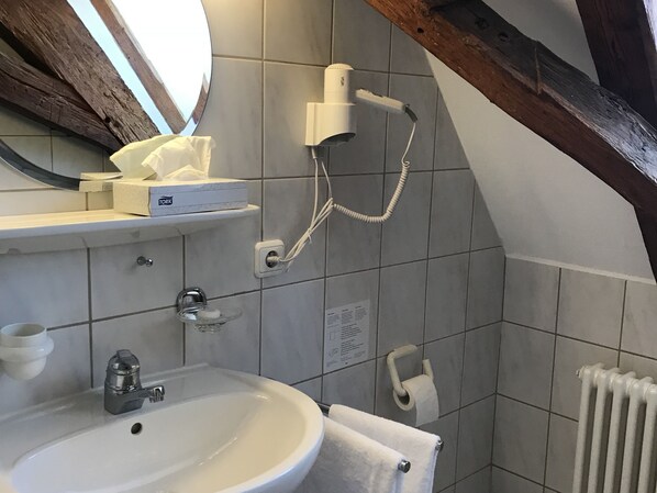 A bathroom with a sink, mirror, towel rack, and a toilet paper holder. - Hotel Hohe Schule (Bad Ueberkingen)