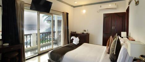 A hotel room with a bed, a TV, a desk, a chair, a balcony with a view, and a wardrobe.