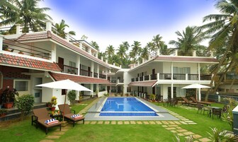 Un hotel con piscina central, varios balcones y abundante vegetación.