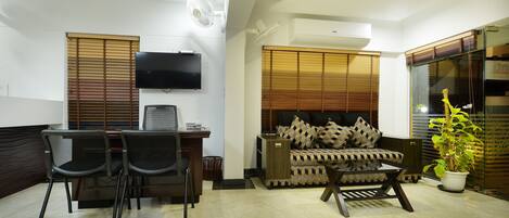 A living room with a TV, two chairs, a sofa, and a potted plant.
