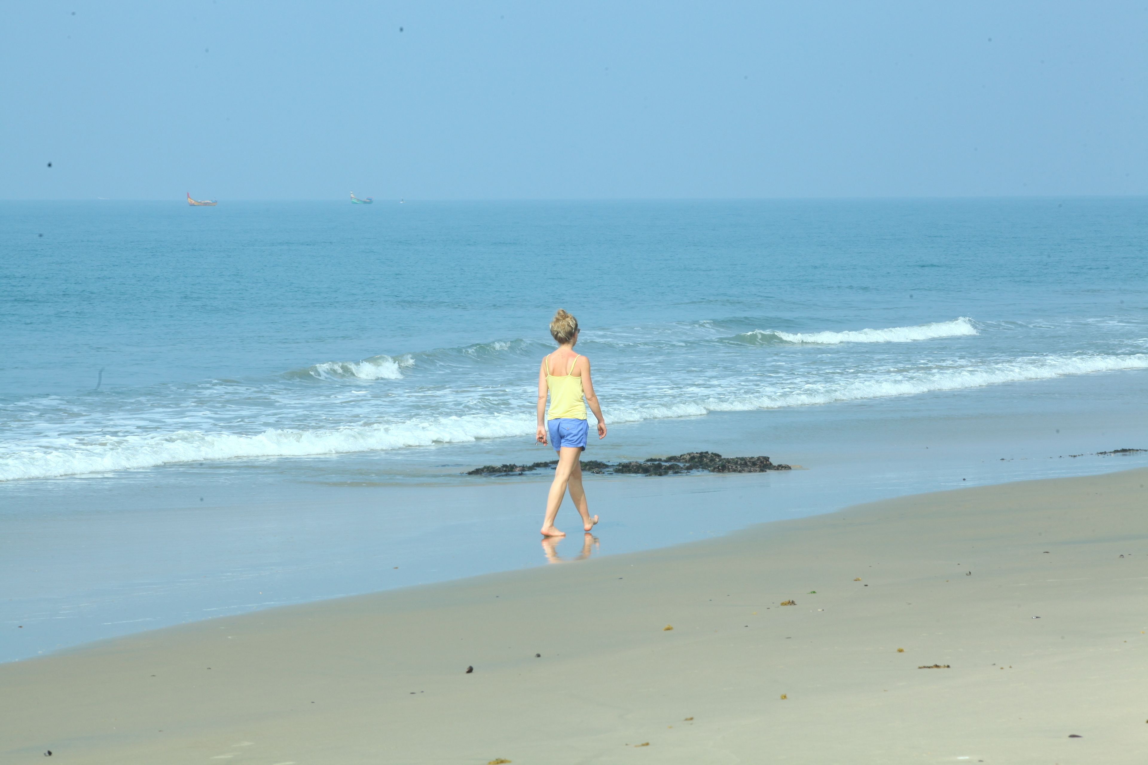 A beach with a person walking towards the water.