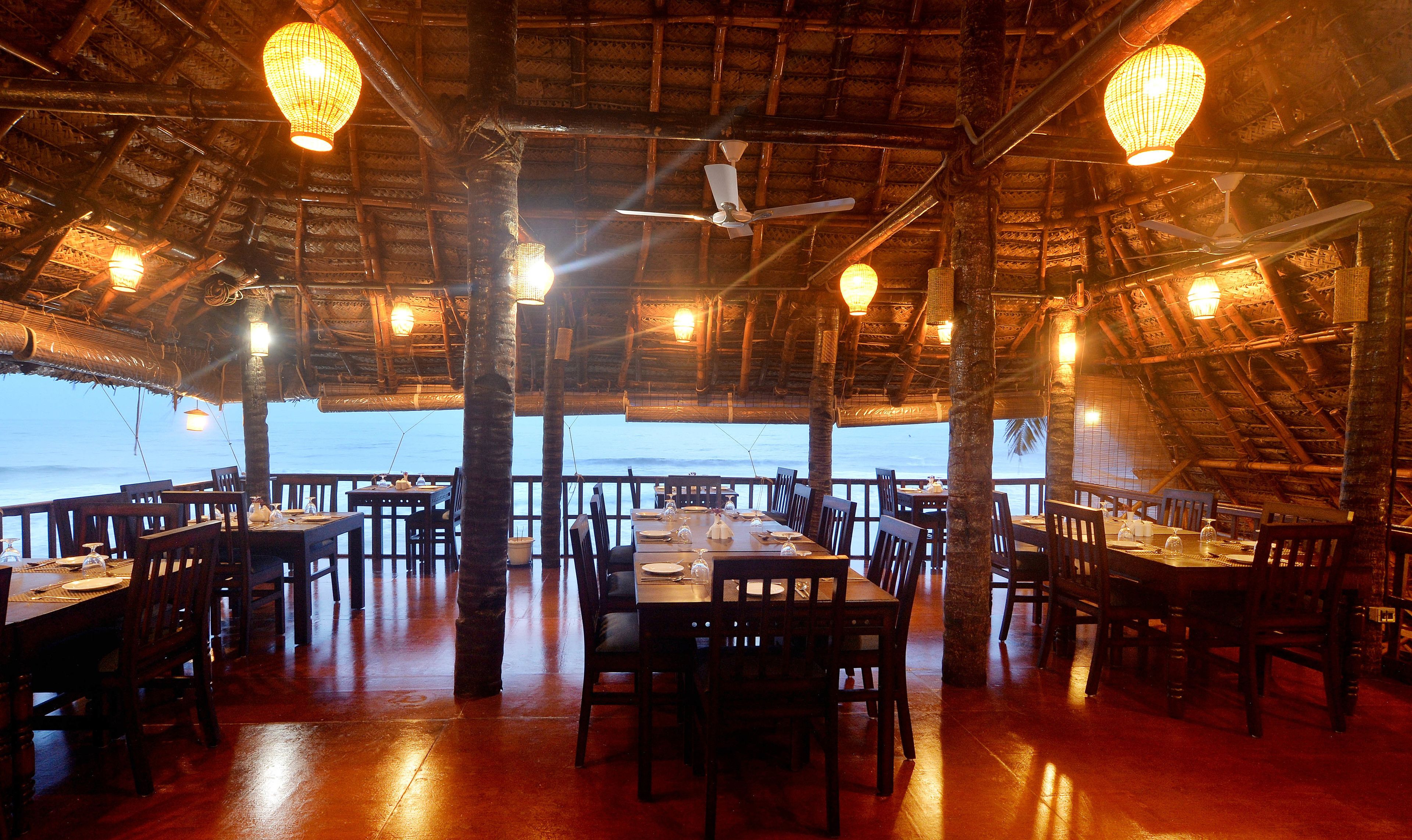 An indoor dining area with tables and chairs, a ceiling fan, and hanging lights.