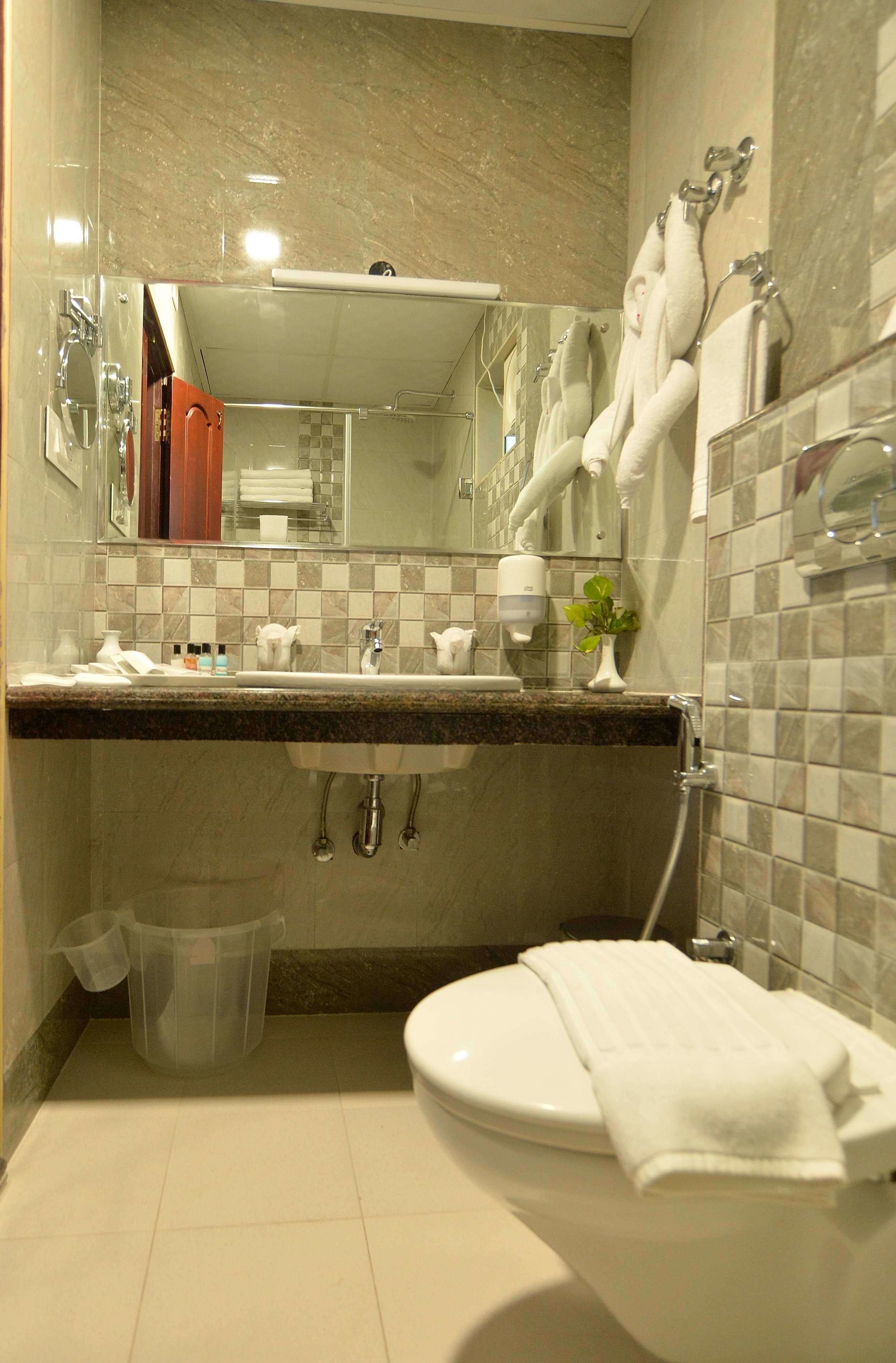 A modern bathroom with a marble vanity, a glass shower enclosure, and a white toilet.
