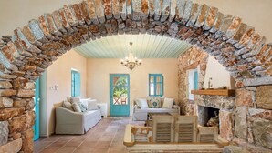 Una sala de estar acogedora con paredes de piedra, chimenea y piso de baldosas.