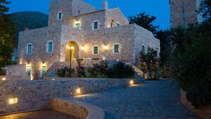 Un edificio de piedra con patio, entrada abovedada y una torre.