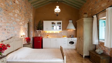 A bedroom with a bed, a red refrigerator, a white cabinet, and a window with curtains.