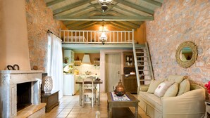 Una habitación acogedora con chimenea, un sofá, una mesa y una zona de cocina al fondo.