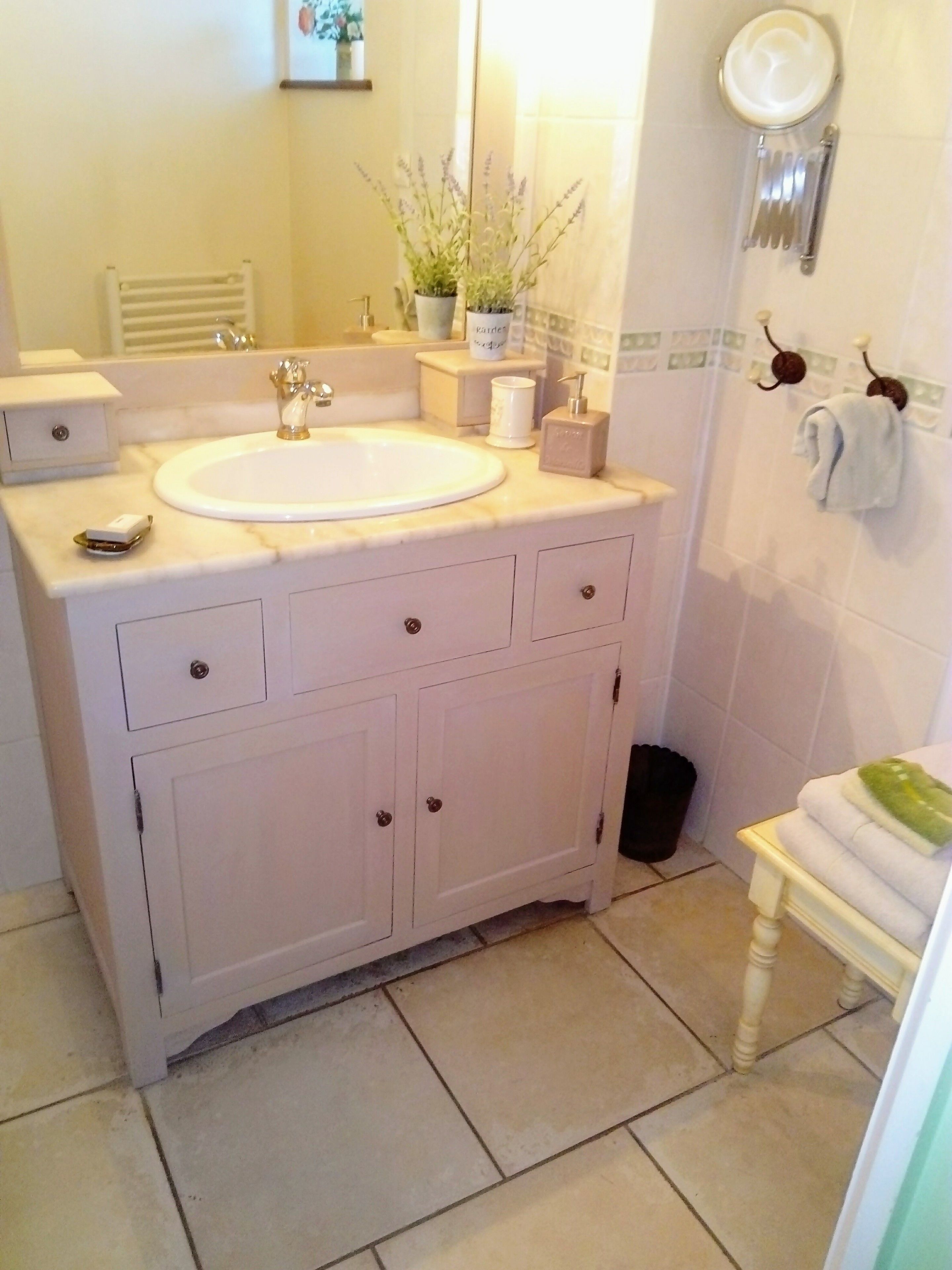 A bathroom with a white sink, vanity, and a mirror. There is a towel rack with a towel and a small potted plant on the vanity.