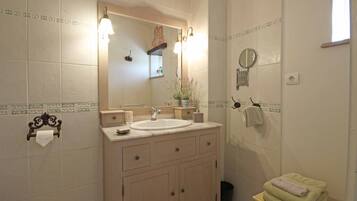 Un baño con lavamanos, espejo, toallero y una planta pequeña en el mostrador.