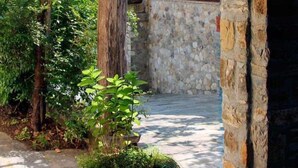 Un arco de piedra que da acceso a un patio con una planta en maceta y una pérgola de madera.