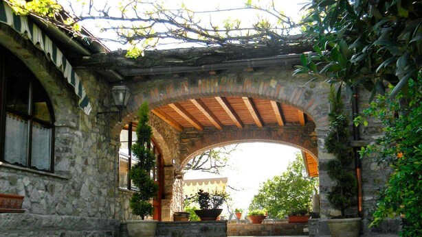 Un arco de piedra con vigas de madera que conduce a un edificio con techo de tejas.