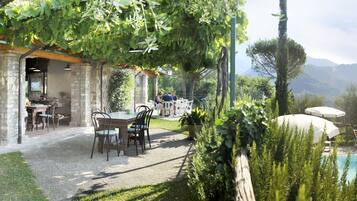 Relax by the pool surrounded by lush greenery and distant mountains in a serene outdoor dining area.