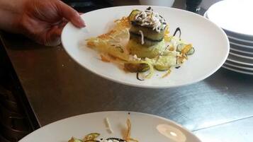 Dos platos blancos con un guiso de verduras rellenas y queso rallado, sostenidos por una persona.