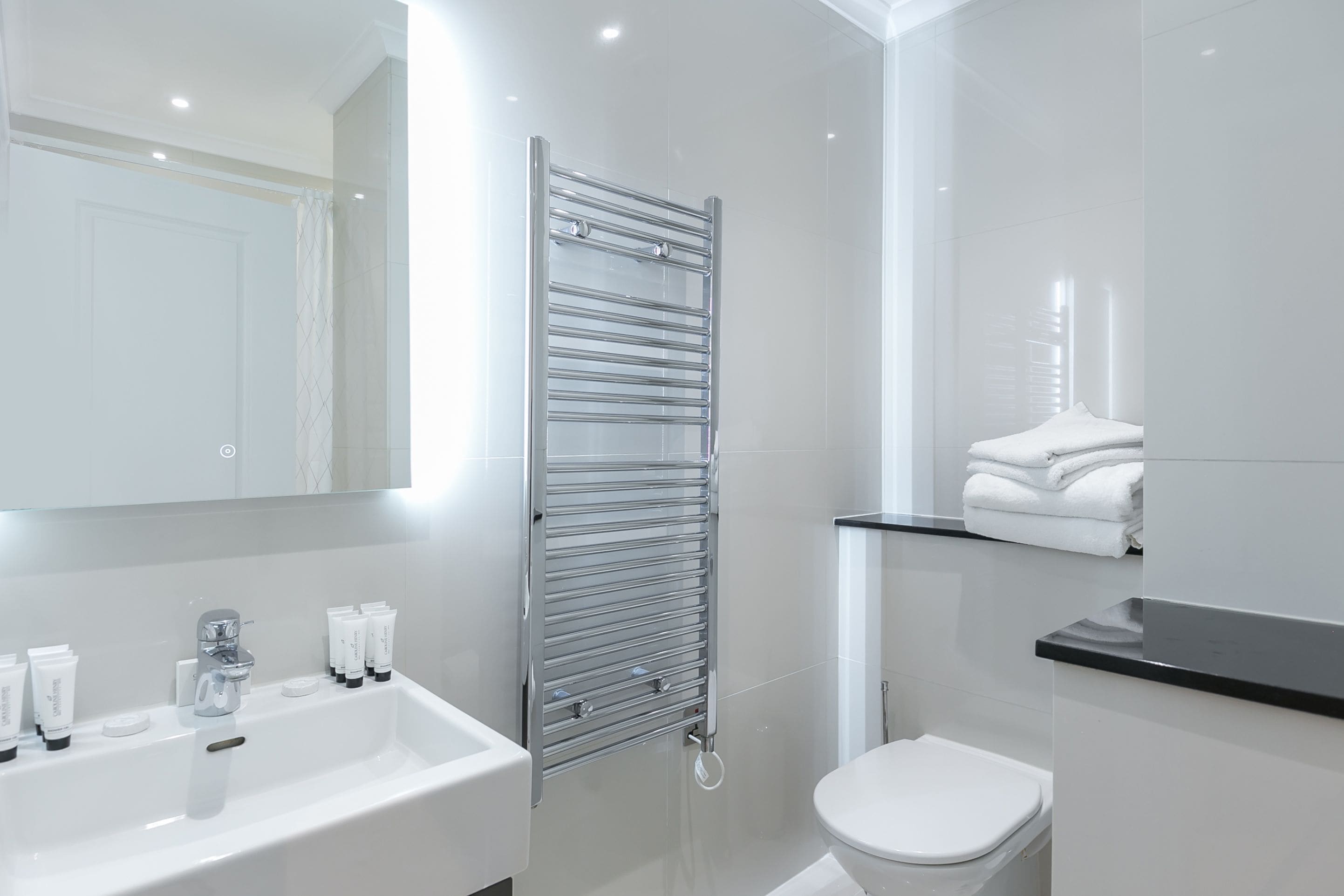 Un baño moderno con lavamanos, espejo y retrete blancos.